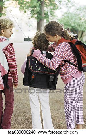 Girl helping younger sister put on backpack View Large Photo Image Stock Image - Girl helping younger sister put on backpack. Fotosearch