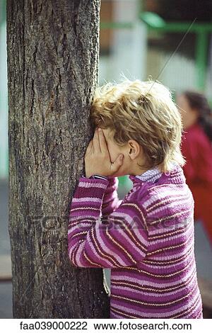 Girl leaning against tree trunk, playing hide-and-seek View Large Photo Image Stock Image - Girl leaning against tree trunk, playing hide-and-seek. Fotosearch