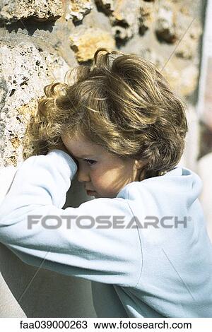 Stock Image - Girl leaning against wall, sulking. Fotosearch