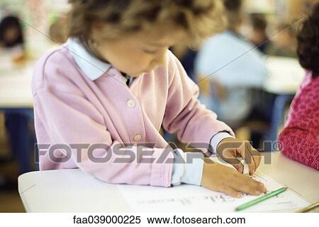 Stock Photography - Girl sitting at desk, erasing writing. Fotosearch
