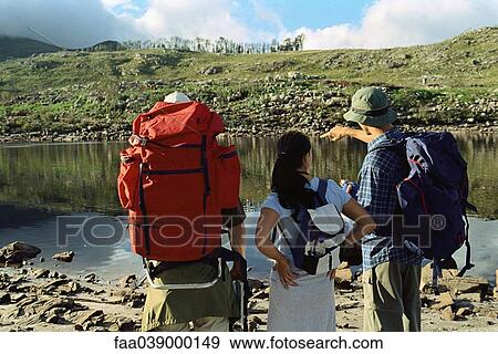 Hikers deciding how to cross pond, rear view View Large Photo Image Stock Photo - Hikers deciding how to cross pond, rear view. Fotosearch