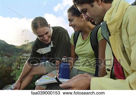 Stock Image - Hikers sitting down, looking at map. Fotosearch