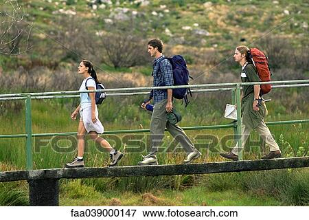 Stock Photo - Hikers walking across footbridge. Fotosearch