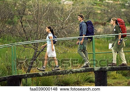 Hikers walking across footbridge View Large Photo Image Stock Photo - Hikers walking across footbridge. Fotosearch