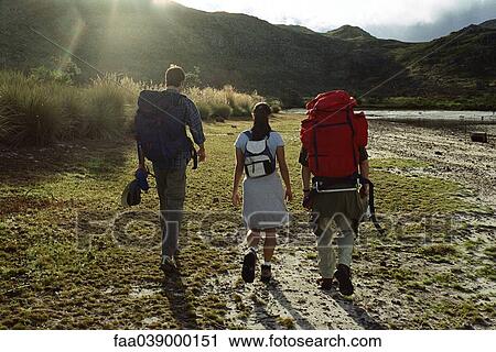 Stock Image - Hikers walking, rear view. Fotosearch