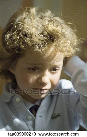 Stock Image - Little girl looking sad, holding head, portrait. Fotosearch