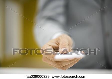 Stock Photo - Man in suit holding out business card, cropped. Fotosearch