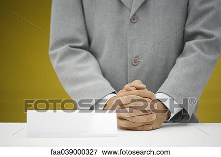 Stock Photo - Man in suit standing at counter next to blank desk tag. Fotosearch