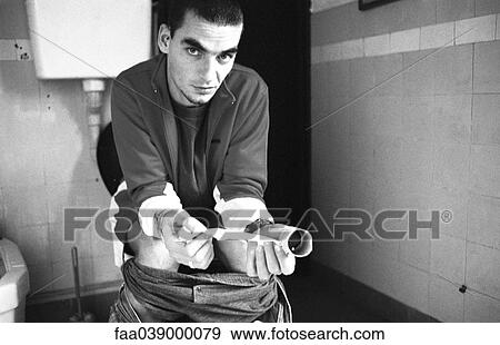 Stock Photo - Man using toilet, holding empty roll of tissue. Fotosearch