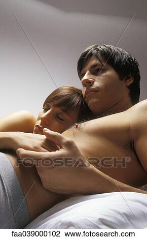 Stock Image - Young couple lying together in bed. Fotosearch