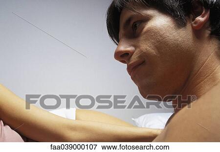 Stock Photo - Young man, bare-chested, looking at woman. Fotosearch