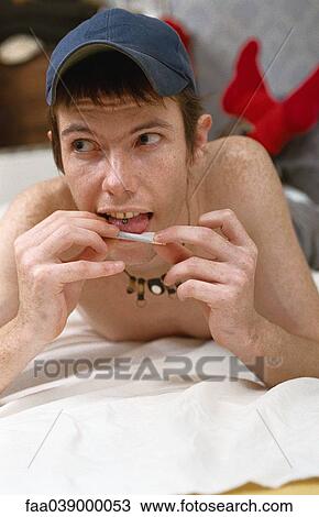 Young man lying in bed rolling joint View Large Photo Image Stock Image - Young man lying in bed rolling joint. Fotosearch