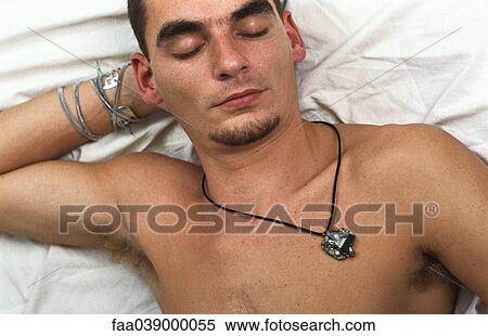Stock Photography - Young man lying on back, hand behind head resting. Fotosearch