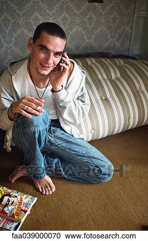 Young man phoning, sitting on floor in bedroom View Large Photo Image Stock Image - Young man phoning, sitting on floor in bedroom. Fotosearch