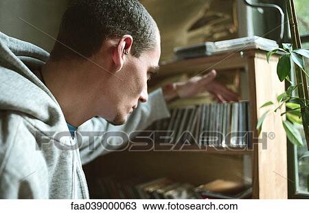 Young man selecting CD from collection on shelf View Large Photo Image Stock Image - Young man selecting CD from collection on shelf. Fotosearch