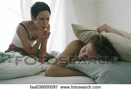Young woman blowing whistle, awakening sleeping young man View Large Photo Image Stock Photo - Young woman blowing whistle, awakening sleeping young man. Fotosearch