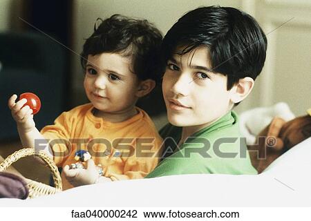 Boy holding little sister, smiling at camera View Large Photo Image Stock Image - Boy holding little sister, smiling at camera. Fotosearch