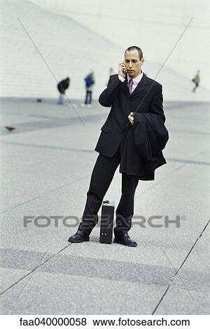 Businessman standing outdoors, talking on cell phone View Large Photo Image Stock Photo - Businessman standing outdoors, talking on cell phone. Fotosearch