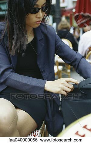 Businesswoman sitting in outdoor cafe, rummaging through briefcase View Large Photo Image Stock Photograph - Businesswoman sitting in outdoor cafe, rummaging through briefcase. Fotosearch