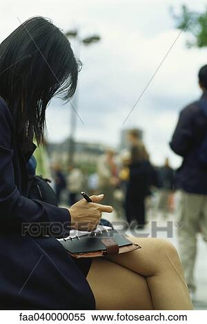 Businesswoman sitting outside, legs crossed, writing in agenda View Large Photo Image Stock Photography - Businesswoman sitting outside, legs crossed, writing in agenda. Fotosearch