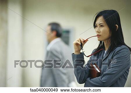 Businesswoman waiting in lobby, holding sunglasses against mouth View Large Photo Image Stock Photo - Businesswoman waiting in lobby, holding sunglasses against mouth. Fotosearch