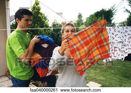 Stock Image - Couple hanging up laundry on clothes-line. Fotosearch