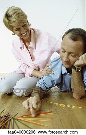 Couple playing pick up sticks on floor View Large Photo Image Stock Photograph - Couple playing pick up sticks on floor. Fotosearch