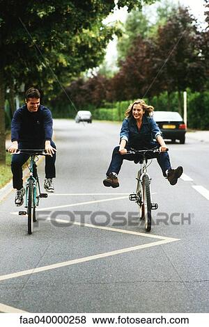 Couple riding bikes, woman doing trick View Large Photo Image Stock Photo - Couple riding bikes, woman doing trick. Fotosearch