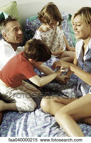 Stock Photography - Family playing together in bed. Fotosearch
