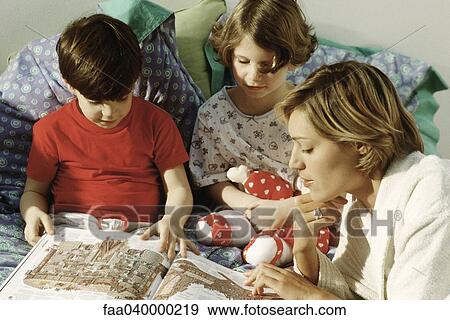 Family reading book in bed View Large Photo Image Stock Photo - Family reading book in bed. Fotosearch