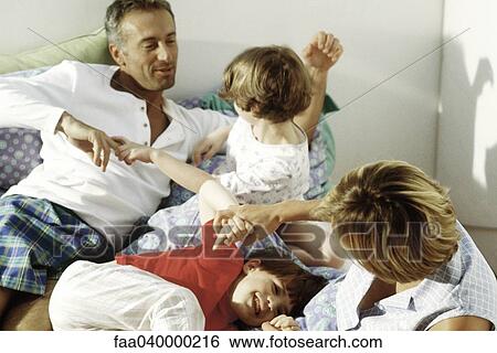 Family rough housing in bed View Large Photo Image Stock Photograph - Family rough housing in bed. Fotosearch