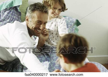 Family together on bed, smiling View Large Photo Image Stock Photo - Family together on bed, smiling. Fotosearch