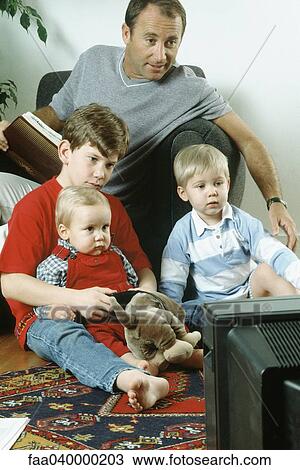 Father and three sons watching TV together View Large Photo Image Stock Image - Father and three sons watching TV together. Fotosearch