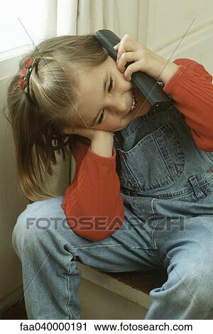 Stock Image - Girl talking on portable phone, head tilted. Fotosearch