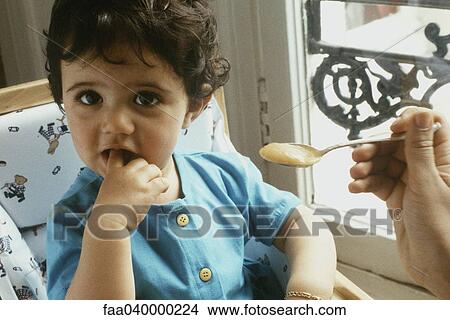 Picture - Little girl being spoon fed. Fotosearch