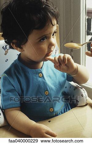 Little girl looking at spoonful of apple sauce View Large Photo Image Stock Photo - Little girl looking at spoonful of apple sauce. Fotosearch
