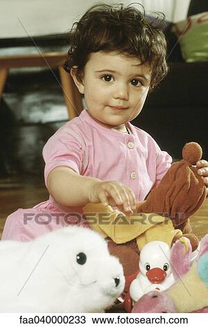 Stock Image - Little girl sitting with toys, portrait. Fotosearch