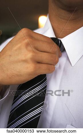 Stock Image - Man adjusting tie, cropped. Fotosearch