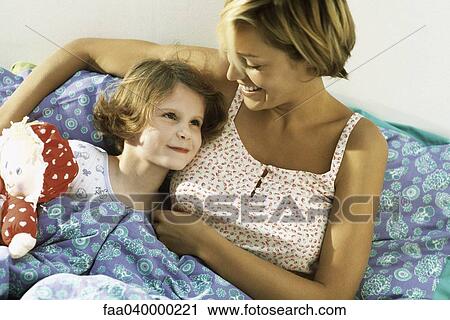 Mother and daughter lying in bed together View Large Photo Image Stock Image - Mother and daughter lying in bed together. Fotosearch