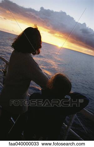 Stock Image - Mother and daughter on deck, looking at sunset. Fotosearch