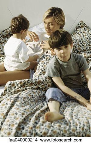 Mother and two children lazing around in bed View Large Photo Image Picture - Mother and two children lazing around in bed. Fotosearch
