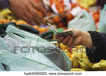 Stock Image - Person paying in market, cropped view. Fotosearch