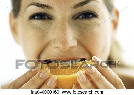 Stock Photo - Woman biting into orange slice. Fotosearch