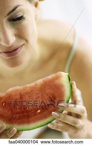 Picture - Woman eating slice of watermelon. Fotosearch
