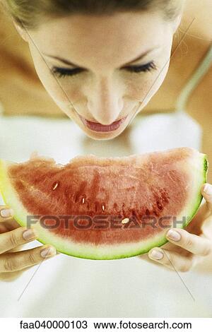 Stock Image - Woman eating slice of watermelon. Fotosearch