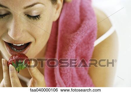 Stock Photograph - Woman eating strawberry, eyes closed. Fotosearch