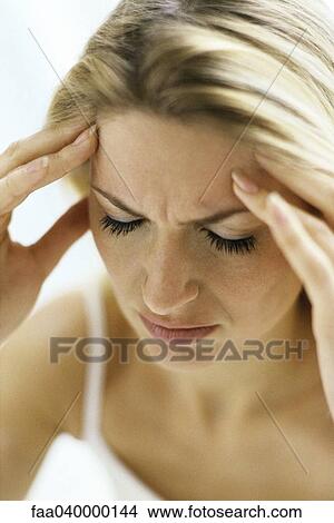 Woman furrowing brow, holding temples View Large Photo Image Picture - Woman furrowing brow, holding temples. Fotosearch