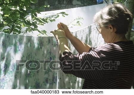Woman hanging sheet on clothes-line View Large Photo Image Stock Image - Woman hanging sheet on clothes-line. Fotosearch