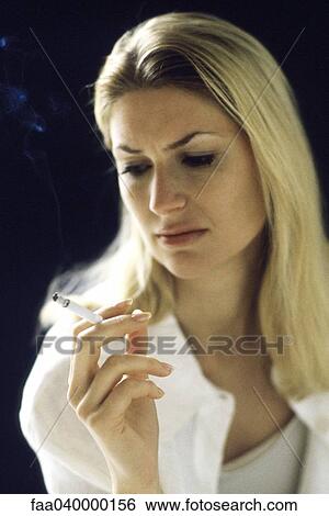 Stock Photograph - Woman holding cigarette, looking down. Fotosearch