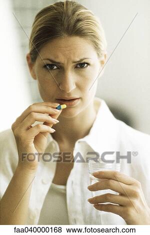 Woman holding pill, frowning at camera View Large Photo Image Stock Photo - Woman holding pill, frowning at camera. Fotosearch